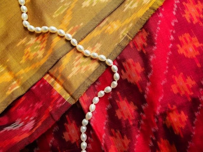silver necklace on red textile